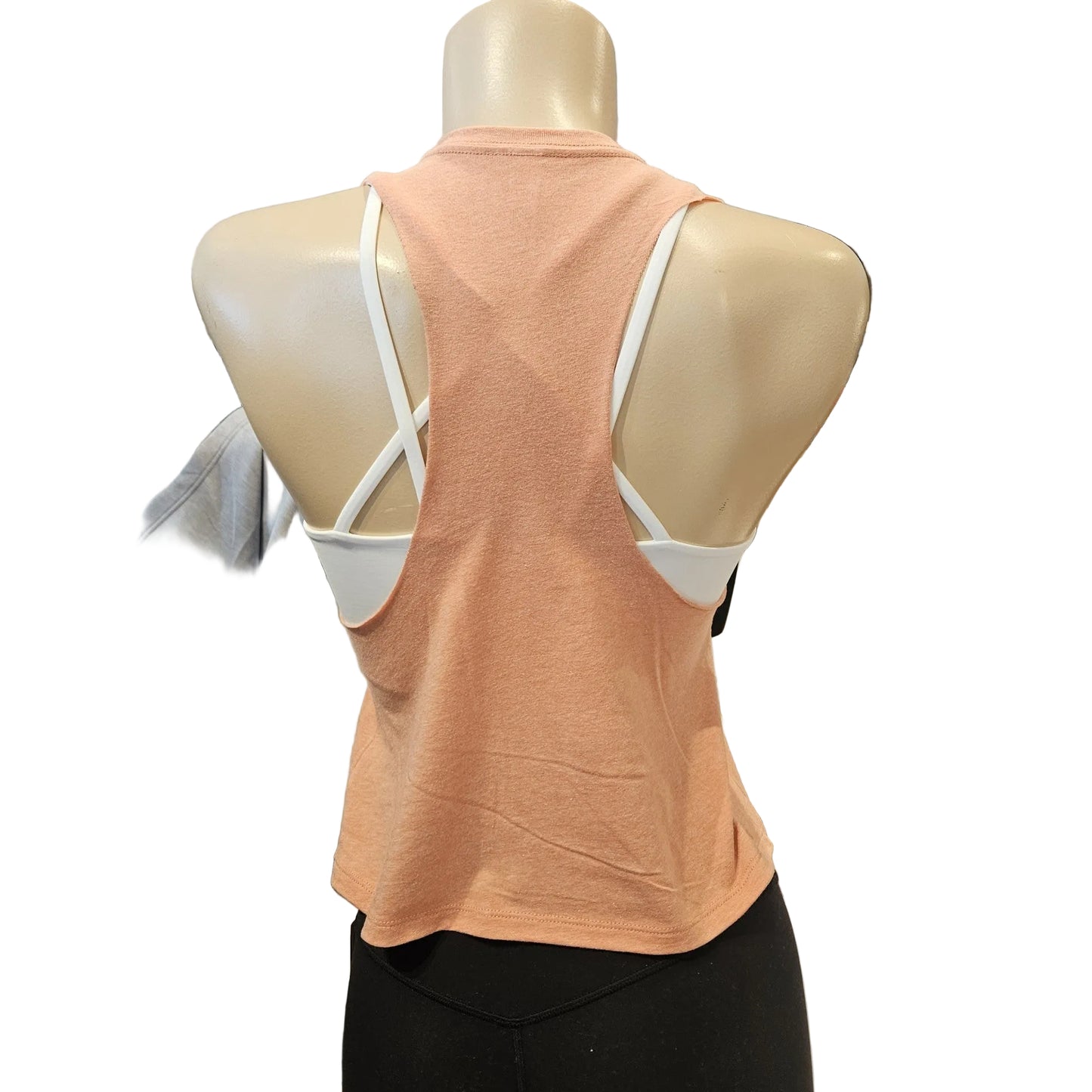 Mannequin wearing a peach tank top with white straps in a clothing store setting.